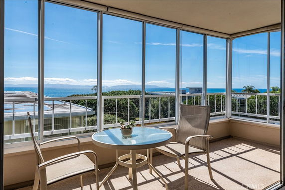 Panoramic view of the ocean and surrounding areas seen from a building with chairs and a table in the foreground.