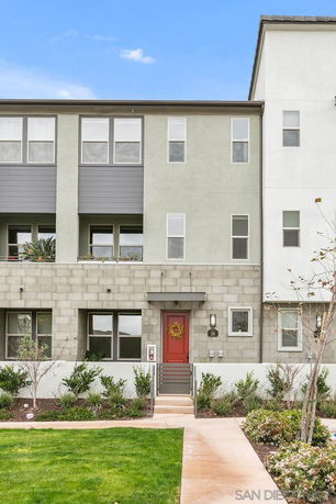 Front view of a three-story townhouse with a red door and modern design features.
