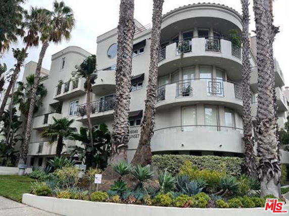 Front view of a multi-story building with balconies and rounded corners.