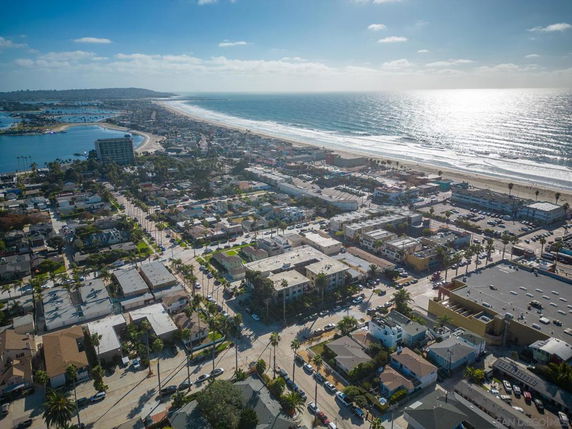 Wide aerial view of a coastal city with buildings, streets, and a beach coastline.