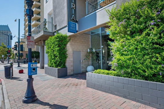 Front view of a modern building entrance with glass doors and potted plants.