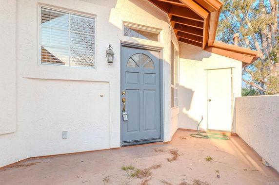 Front entry view of a house with a blue door and adjacent window.