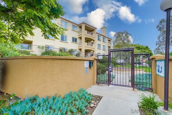 Front view of a multi-story residential building with a gated entrance.