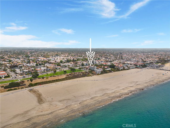 Panoramic view of a coastal city with a beach in the foreground.