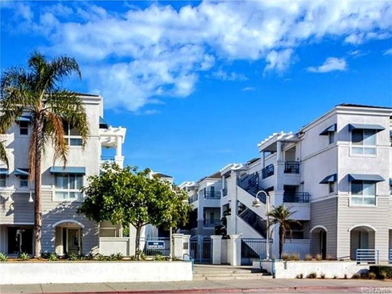 Front view of an apartment building with multiple balconies and a white exterior.