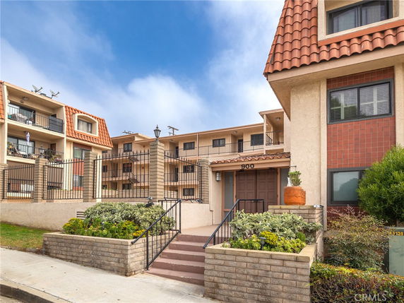 Front view of a multi-story apartment building with a gated entrance.