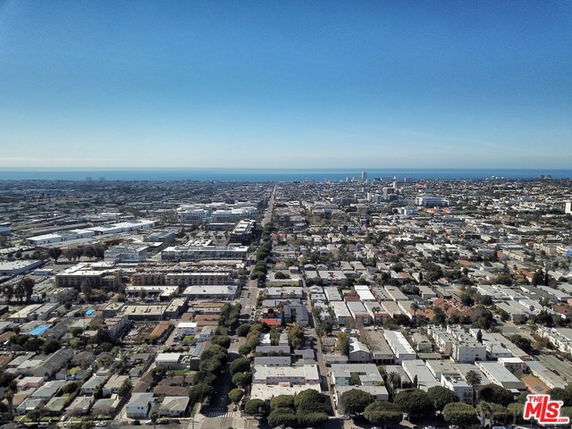 Wide-angle aerial view of a cityscape with buildings and a distant ocean horizon.