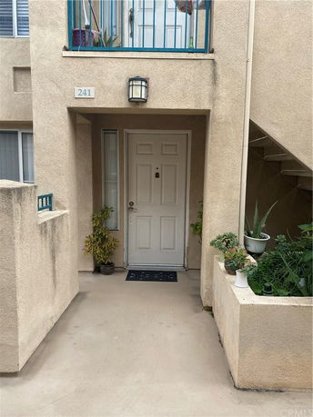 Front view of a building entrance with a white door and small potted plants.