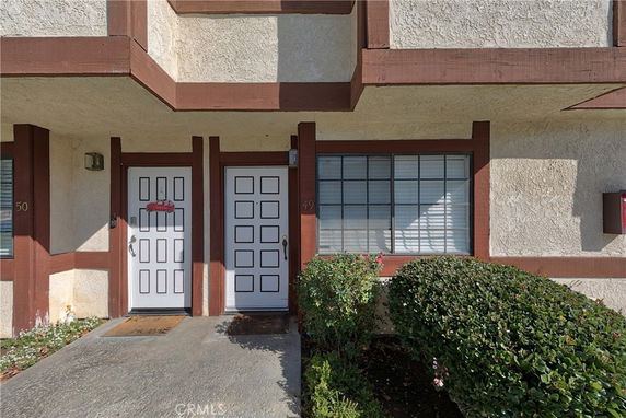 Front view of a building with two doors and a window, featuring a beige exterior with brown trim.