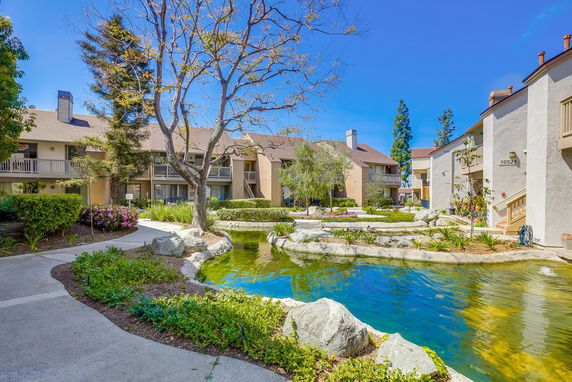 View of a residential complex with pathway and pond.