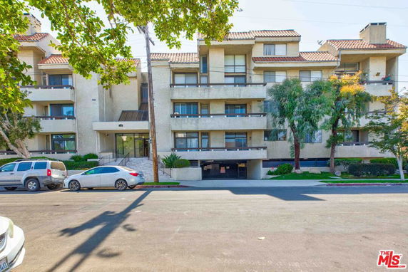 Front view of a multi-story residential building with a central entrance and balconies.