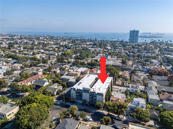 Aerial view of a coastal city with multiple residential buildings and a glimpse of the ocean in the background.
