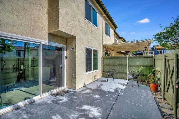 View of a two-story house with a fenced patio area and outdoor seating.