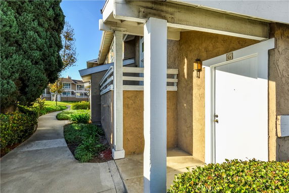 Front view of a building entrance with a white door and adjacent porch area.