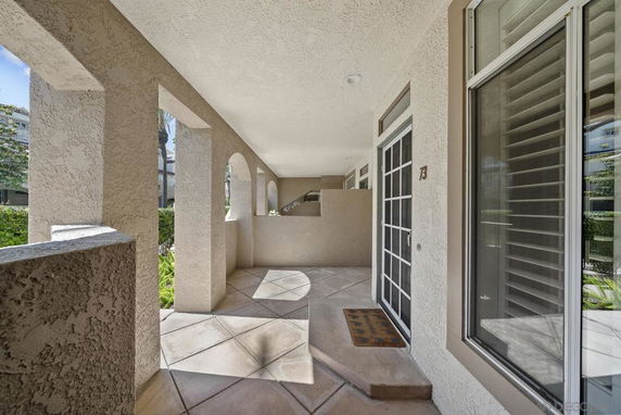 Covered outdoor walkway with arched openings and tiled flooring.