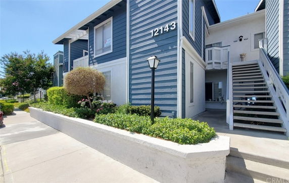 Front view of a multi-story residential building with blue and white siding and an outdoor staircase.
