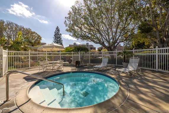 Outdoor area with a small round swimming pool surrounded by lounge chairs and a table with an umbrella.