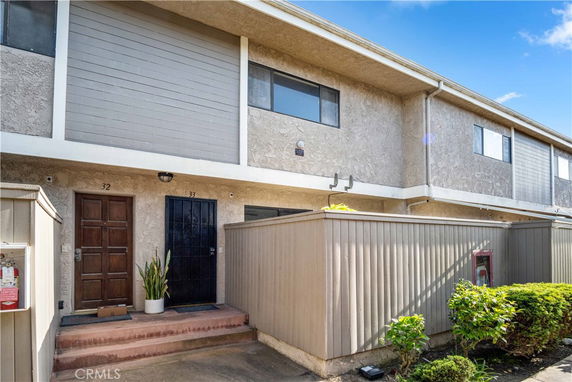 Front view of a two-story townhouse with wooden doors and small patios.