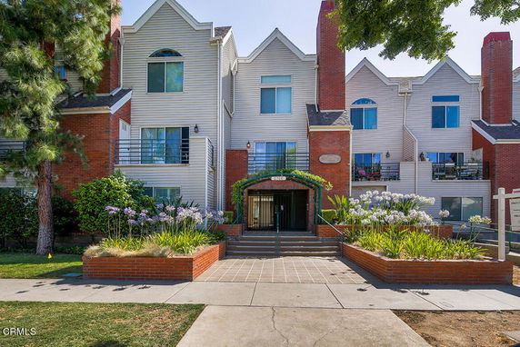 Front view of a multi-story residential building with brick accents and multiple balconies.