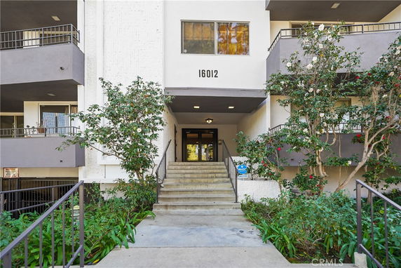Front view of a multi-story building with stairs leading to the entrance.
