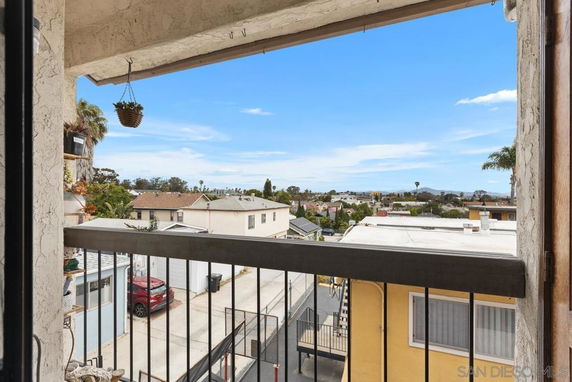 View from a building overlooking residential rooftops and distant landscape.