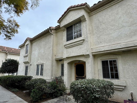 Front view of a two-story house with textured walls and a red tile roof.