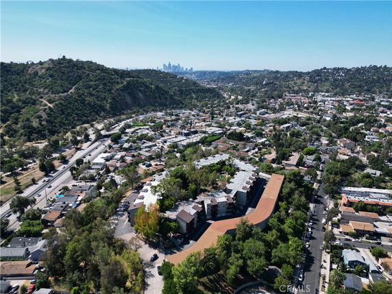Aerial panoramic view of a residential area with hills and city skyline in the background.