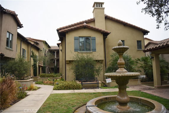 Front view of a multi-story house with a fountain in front.