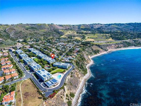 Wide angle view of coastal area with buildings and natural landscape.