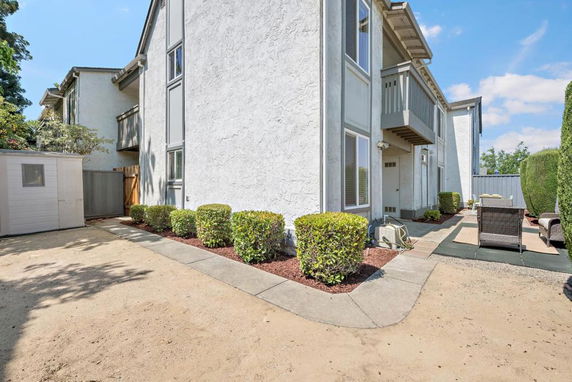 Side view of a multi-story house with a small patio area.