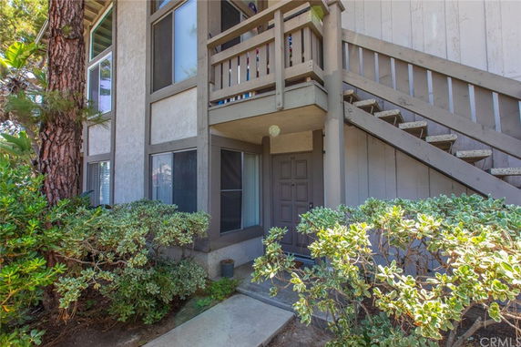 Front view of a residential building with stairs leading to an upper level entrance.