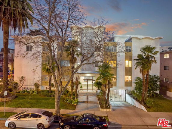 Front view of a multi-story residential building with unique wavy roof design.