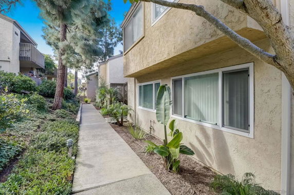 Side view of a beige multi-story residential building with large windows.