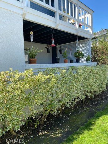 View of a house with a balcony and potted plants on the lower level.