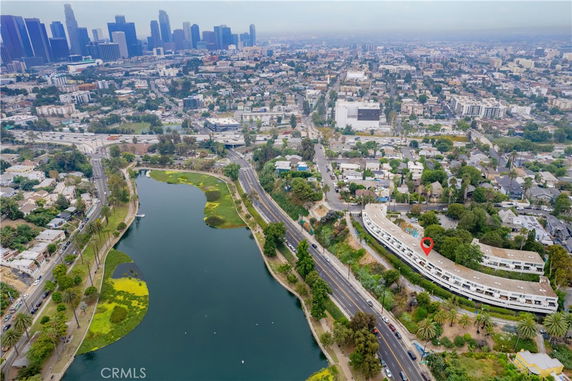 Aerial panoramic view of a cityscape with a curved building by a lake.