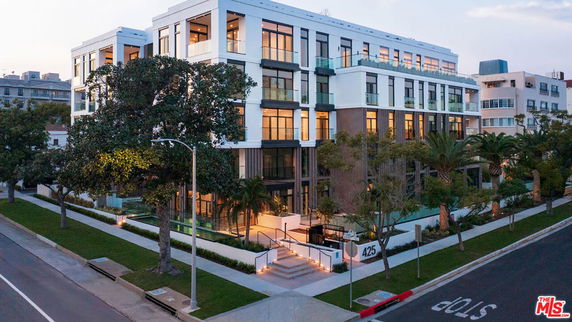 Front view of a multi-story modern apartment building with large windows.