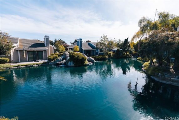 View of houses surrounded by a landscaped pond and trees.