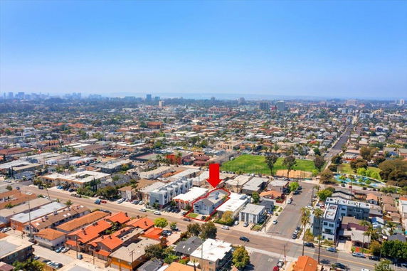 Wide angle view of a city neighborhood with a red arrow indicating a specific building.