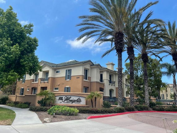 Front view of a multi-story residential building with surrounding palm trees.