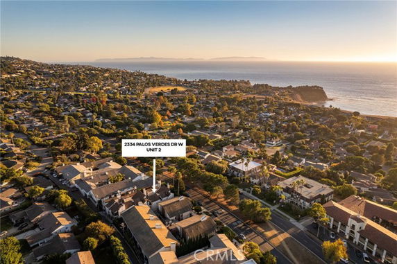 Wide-angle view of a coastal residential area with numerous houses and the ocean in the background.