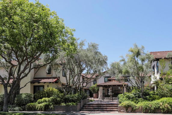 Front view of a two-story residential building with a red-tiled roof and gated entrance.