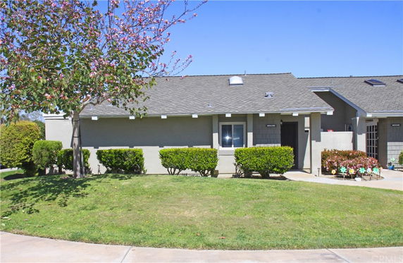 Front view of a single-story house with a sloped roof and small bushes.