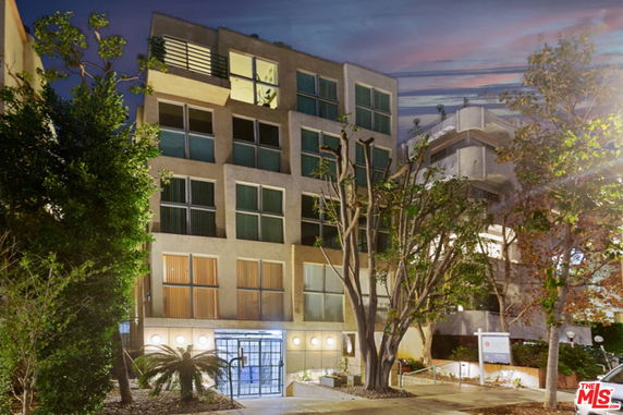 Front view of a multi-story residential building with large windows and a gated entrance.