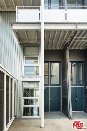 View of a modern multi-level building facade with metal siding and large windows.