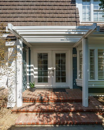 Front view of a house with French doors and a pergola.