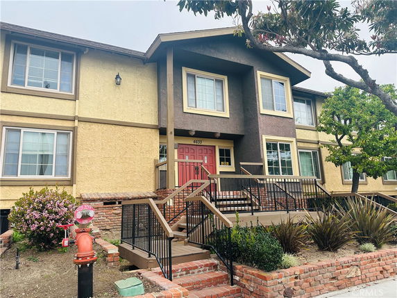 Front view of a two-story house with a red entrance door and multiple windows.