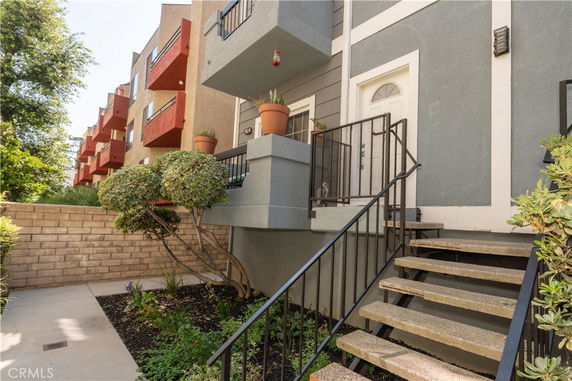 Front view of a building entrance with stairs and potted plants.