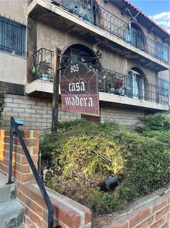 Front view of a multi-story building with iron balconies and an entrance sign that reads 'casa madera'.