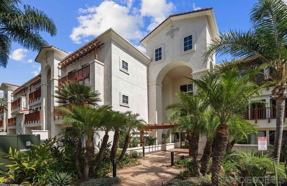 Front view of a multi-story residential building with balconies and an arched entrance.