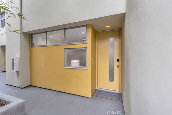 Front view of a modern building entrance with yellow accent.